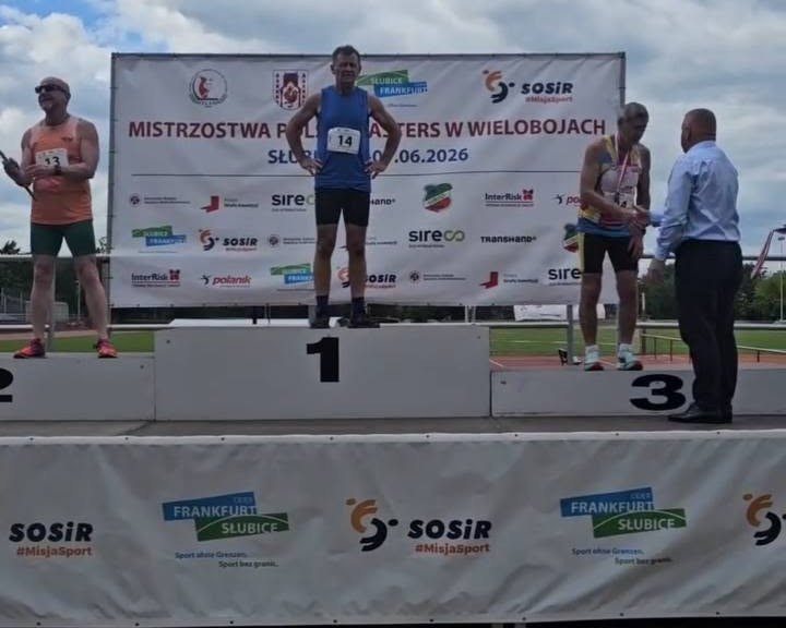 Trzej panowie w sportowych strojach stoją na podium