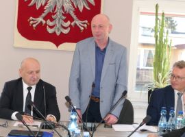 Trzech mężczyzn za stołem prezydialnym 