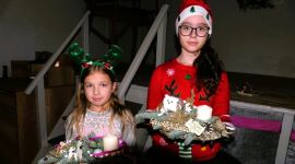 Dwie dziewczynki trzymające w ręku stroiki bożonarodzeniowe 