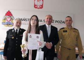 Trzej mężczyźni i dziewczynka. Dziewczynka trzyma w ręku dyplom 