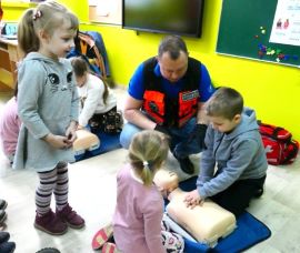 Ratownik medyczny tłumaczy dzieciom zasady udzielania pierwszej pomocy 