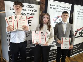 Grupa uczniów stoi obok siebie. Wszyscy trzymają w dłoniach dyplomy 