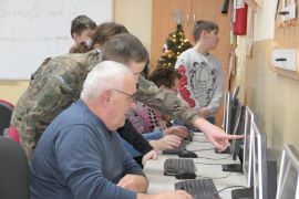 Seniorzy i uczniowie przy komputerach 