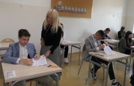 Uczniowie siedzą w szkolnych ławkach 