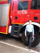 Chłopiec stoi obok samochodu pożarniczego 