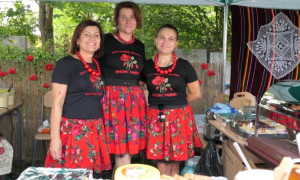 Trzy uśmiechnięte kobiety stoją obok siebie. Kobiety ubrane są w kolorowe stroje 