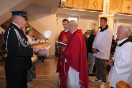 Duchowny błogosławi dożynkowy bochen chleba 