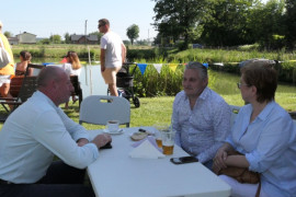 Kobieta i dawaj mężczyźni siedzą przy stoliku. Trwa rodzinny piknik 