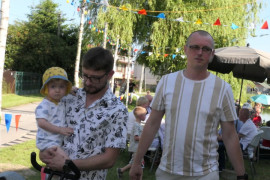 Dwaj mężczyźni i dziecko. Jeden z mężczyzn trzyma dziecko na ręku 