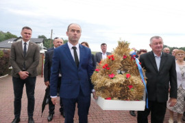 Dwaj panowie niosą dożynkowy wieniec 