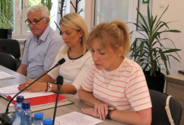 Dwie kobiety i mężczyzna siedzą przy stole. Jedna z kobiet przemawia 
