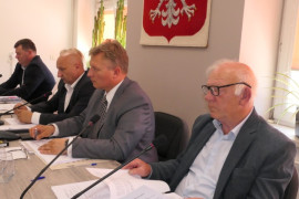 Osoby siedzą za stołem prezydialnym. Posiedzenie Rady Gminy