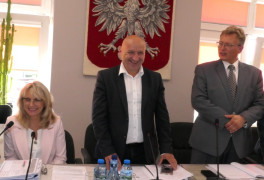 Dwaj mężczyźni i kobieta. Kobieta siedzi, mężczyźni stoją 