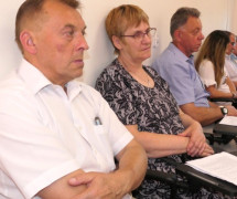 Osoby siedzą obok siebie na krzesłach 