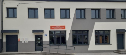 Budynek biblioteki w Strzałkowie. Elewacja budynku utrzymana jest w szarych barwach 