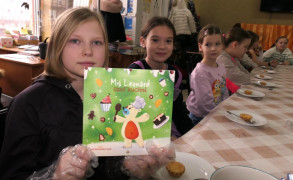 Dziewczynka trzyma w ręku książkę "Miś Leonard - szef kuchni"