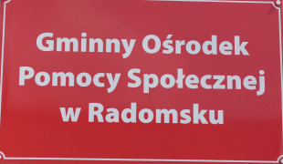 Czerwona tablica, na której widnieje napis: Gminny Ośrodek Pomocy Społecznej w Radomsku