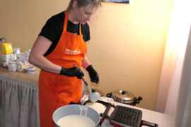 Kobieta nalewa ciasto na gofry do gofrownicy 