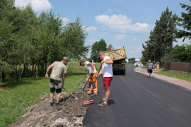 Drogowcy podczas prac drogowych. W dali widać samochód ciężarowy 