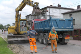 Drogowcy, koparka, samochód z odkrytą przyczepą - trwa przebudowa drogi 