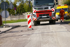 Jezdnia w remoncie. Widoczny samochód ciężarowy oraz biało-czerwone pachołki