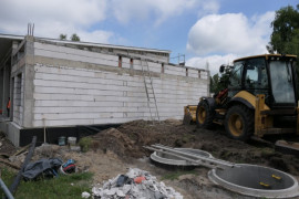 Obiekt w trakcie budowy: widoczne traktor i mury budowanych garaży z przeznaczeniem dla OSP w Dąbrówce