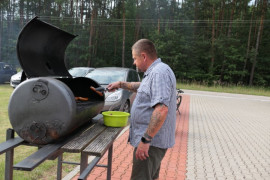 Mężczyzna stojąc przy grillu przygotowuje smaczne potrawy