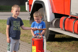 Dwaj mali chłopcy stoją obok wozu strażackiego 