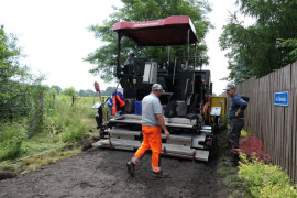 Drogowiec i maszyna do budowy drogi podczas remontu nawierzchni