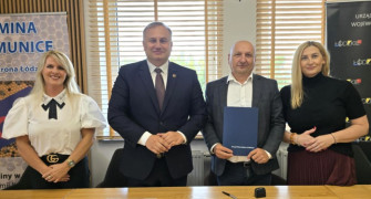 Cztery osoby: dwie kobiety i dwaj mężczyźni stoją obok siebie. Jeden z mężczyzn trzyma w dłoniach dokumenty