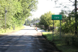 Droga i zielona tablica informacyjna z napisem Lipie 