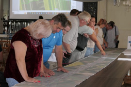 Grupa osób podczas zapoznawania się z dokumentami wyłożonymi na stołach