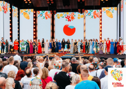 Grupa osób: jedni są na scenie, inni stoją przez nią 