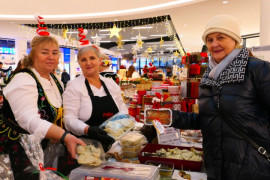 Trzy kobiety przy stoisku wystawienniczym. Panie pokazują pierogi i pasztet 