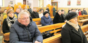 Osoby siedzą w kościelnych ławkach 
