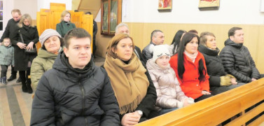 Osoby siedzą w kościelnych ławkach 