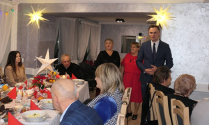 Spotkanie wigilijne: grupa osób siedzi przy stole 