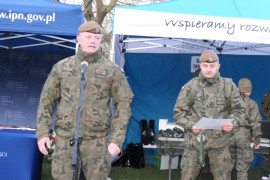 Dwaj żołnierze. Jeden z nich stoi przy mikrofonie i przemawia 