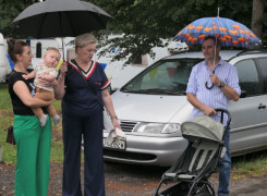 Trzy osoby stoją obok siebie. Kobieta trzyma na ręku dziecko