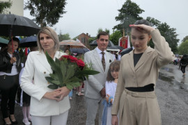 Grupa osób, jedna z nich - kobieta trzyma w ręku kwiaty
