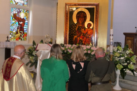 Ksiądz i wierni klęczą przed obrazem  Matki Bożej 
