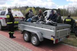 Osoby wkładają na przyczepkę samochodowa worki, w których znajdują się odpady zebrane podczas sprzątania rzeki Warty 