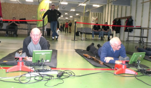Dwaj mężczyźni przygotowują się do oddania strzałów z broni na strzelnicy sportowej 