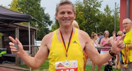 Piotr Płoskoński podczas biegu w Niemczech. Ubrany jest w żółtą koszulkę, na której widnieje numer startowy. 