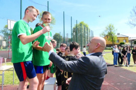 Mężczyzna wręcza puchar zawodnikom 