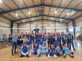 Grupa mężczyzn w niebieskich strojach sportowych. Jedni stoją inni siedzą