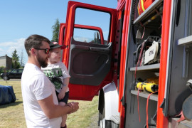 Mężczyzna z małym chłopcem na ręku podczas oglądania wozu strażackiego 