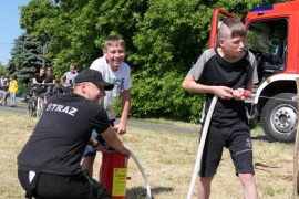 Dwóch chłopców i strażak podczas zabawy przygotowanej przez strażaków