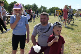Mężczyzna z dwójka dzieci podczas festynu. Dzieci jedzą lody