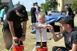 Dziewczynka i dwóch strażaków podczas pompowania wody